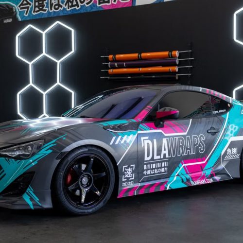 Dynamic photo of a sleek sports car with colorful custom vinyl wrap by DLA Wraps in a shop setting.